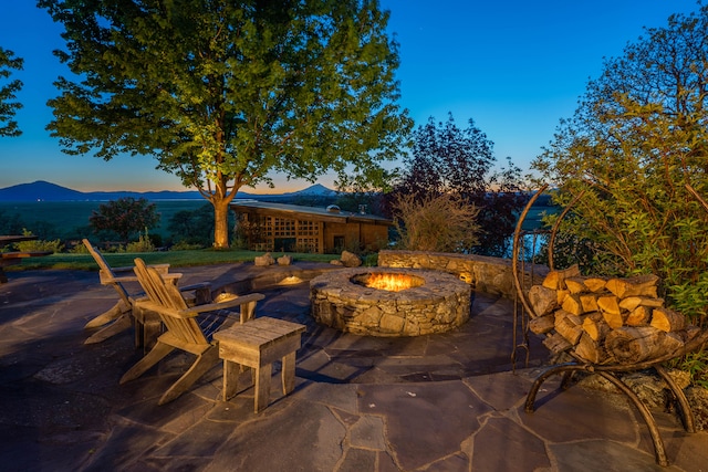 patio terrace at dusk featuring a mountain view and an outdoor fire pit