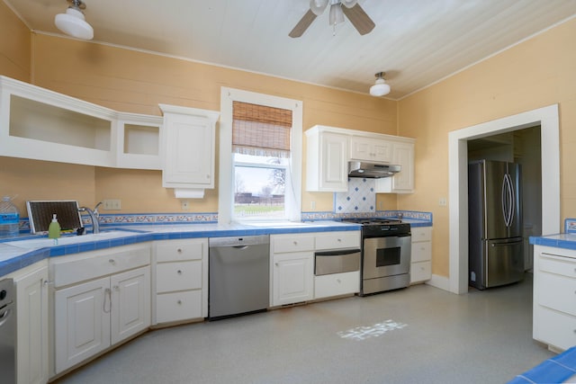 kitchen featuring tasteful backsplash, stainless steel appliances, sink, tile countertops, and white cabinetry