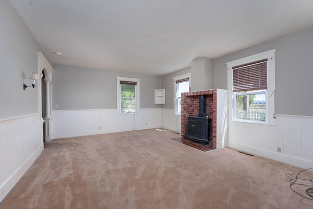 unfurnished living room featuring carpet and a wood stove