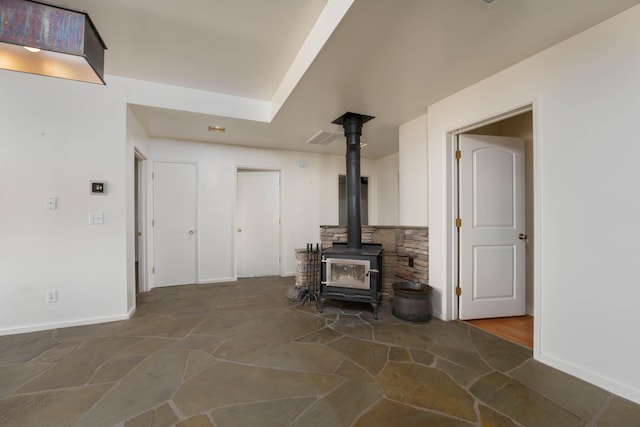 27744 Lee Rd, Mcarthur, CA 96056 - unfurnished living room with baseboards, a wood stove, and stone floors