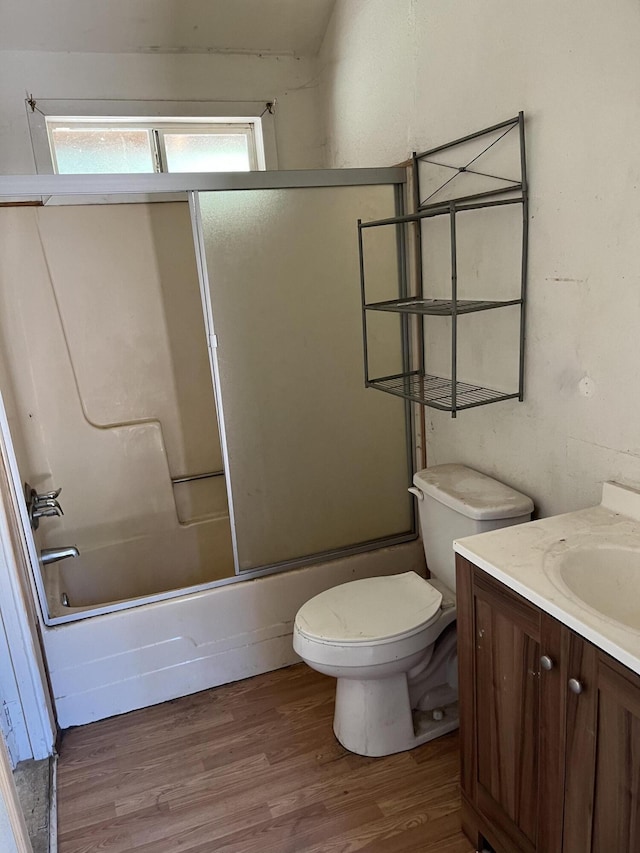 full bathroom with wood-type flooring, enclosed tub / shower combo, vanity, and toilet