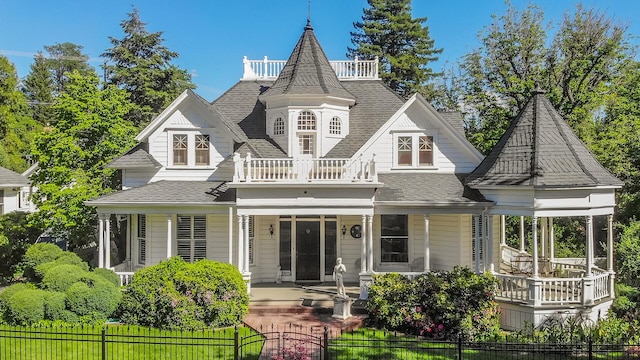 rear view of property with a porch and a balcony