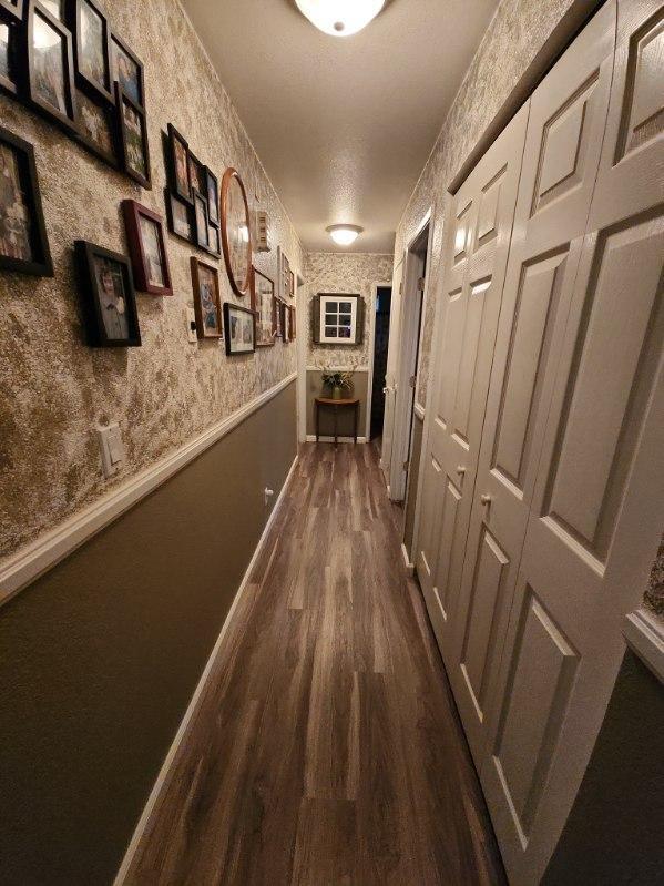 hallway with a textured ceiling and dark hardwood / wood-style floors