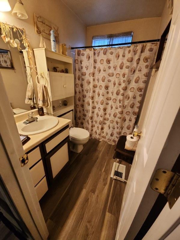 bathroom with toilet, hardwood / wood-style flooring, walk in shower, and vanity