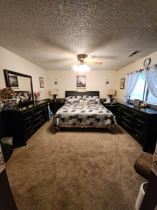 carpeted bedroom featuring a textured ceiling and ceiling fan