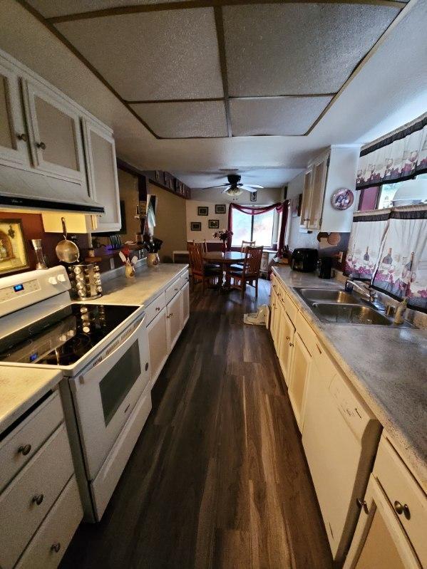 kitchen with white appliances, ceiling fan, dark wood-type flooring, sink, and white cabinetry