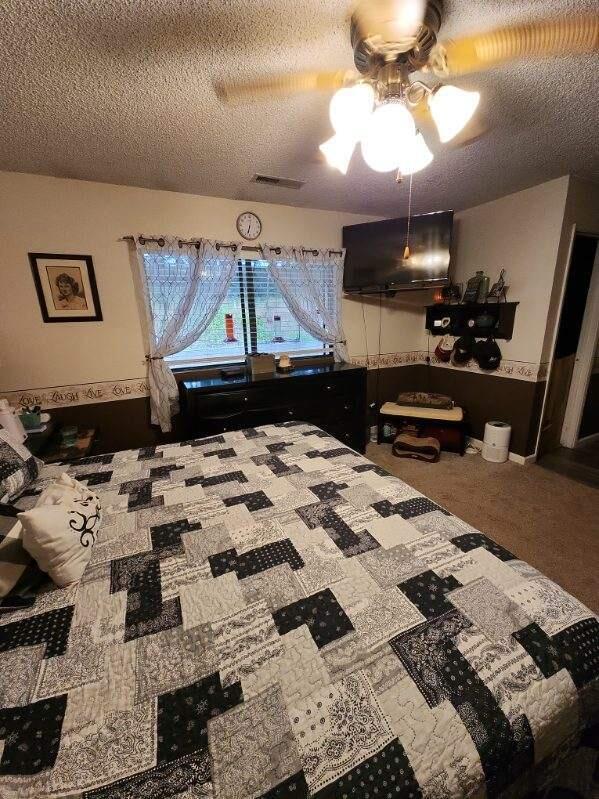 bedroom with a textured ceiling, ceiling fan, and carpet