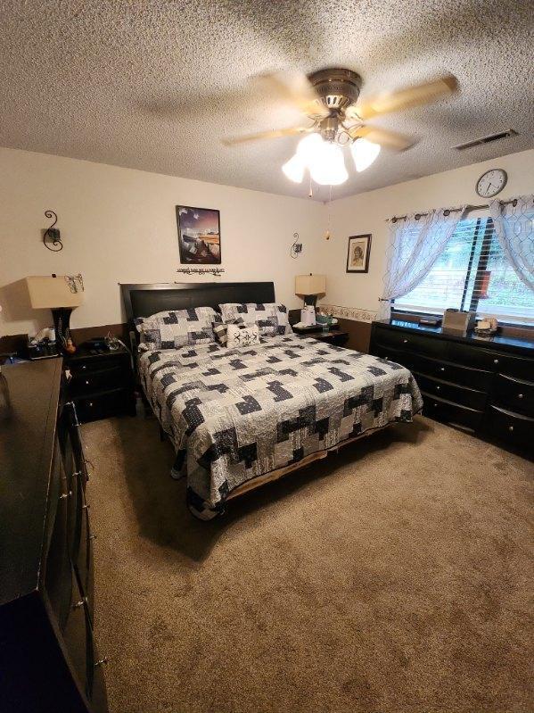 carpeted bedroom featuring a textured ceiling and ceiling fan