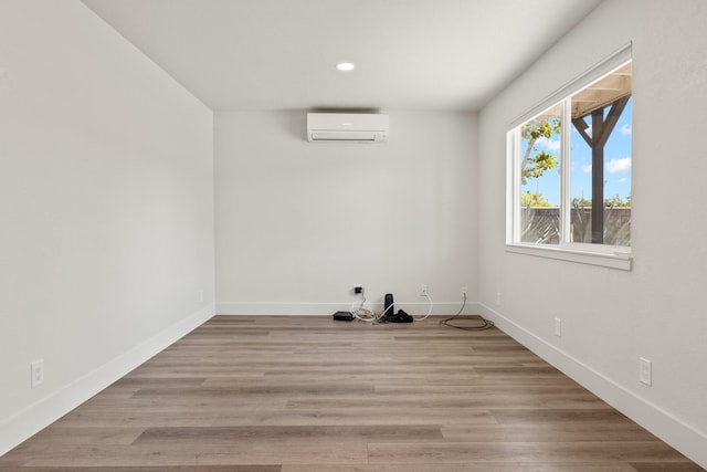 spare room featuring a wall unit AC and light hardwood / wood-style floors