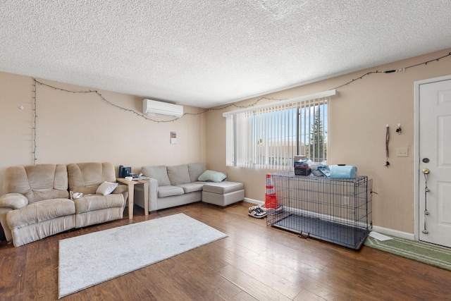 living room with an AC wall unit, wood-type flooring, and a textured ceiling