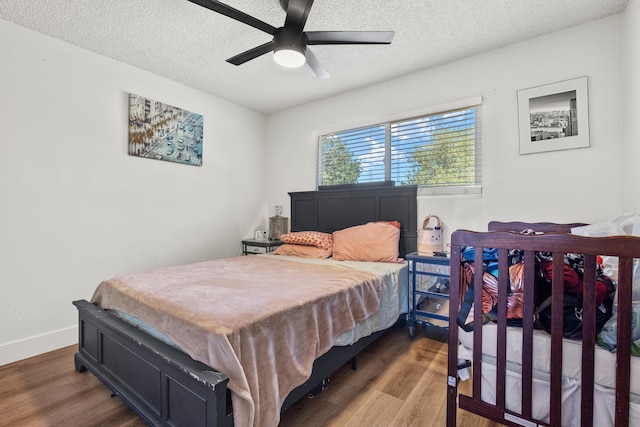 bedroom with ceiling fan, wood-type flooring, and a textured ceiling