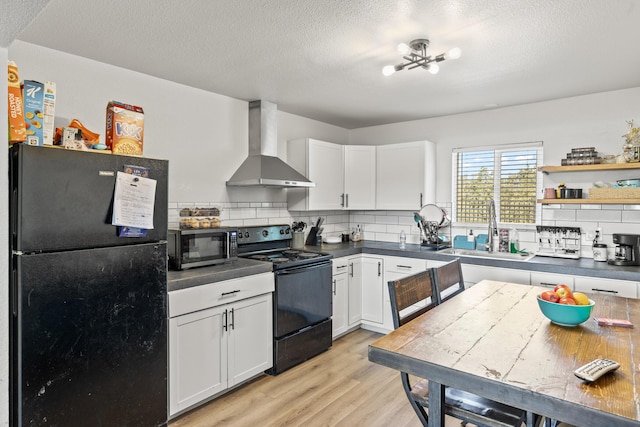 kitchen featuring white cabinetry, sink, black appliances, and wall chimney range hood