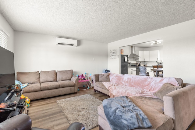 living room with light hardwood / wood-style floors, an AC wall unit, and a textured ceiling