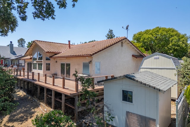 back of property with a deck and a shed