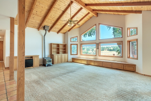 unfurnished living room featuring a wood stove, beamed ceiling, carpet floors, and high vaulted ceiling