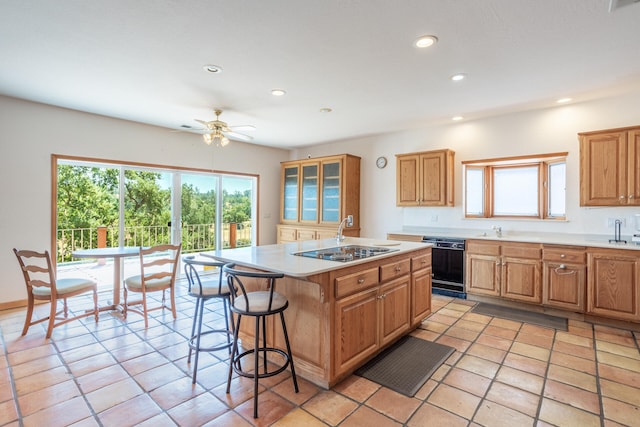 kitchen featuring black appliances, a breakfast bar, light tile patterned floors, a center island, and ceiling fan