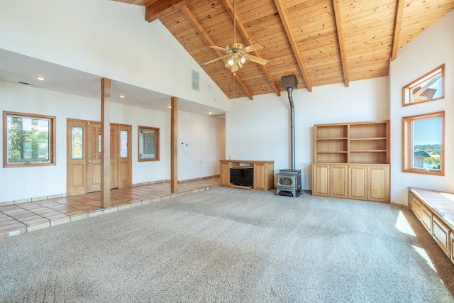 unfurnished living room with ceiling fan, a wood stove, wooden ceiling, high vaulted ceiling, and light carpet