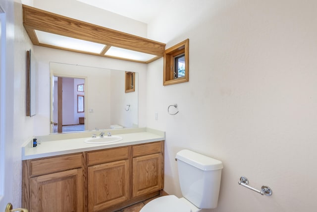 bathroom featuring vanity, toilet, and a healthy amount of sunlight