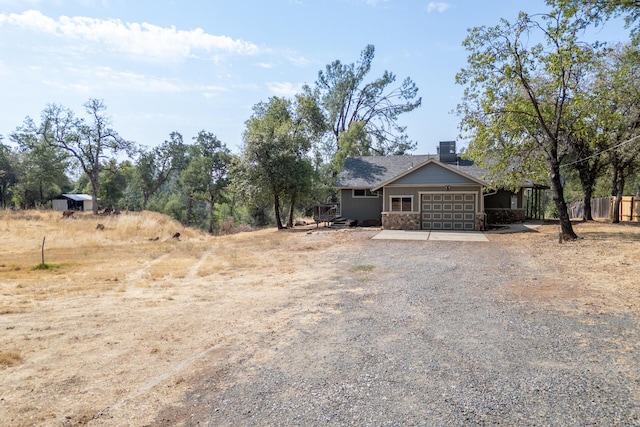 exterior space with central AC, driveway, a chimney, and an attached garage