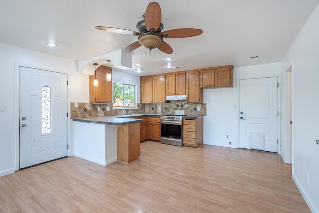 kitchen with brown cabinetry, stainless steel electric range oven, under cabinet range hood, and a peninsula