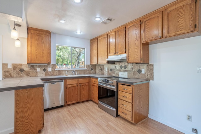 kitchen featuring visible vents, appliances with stainless steel finishes, brown cabinets, under cabinet range hood, and a sink