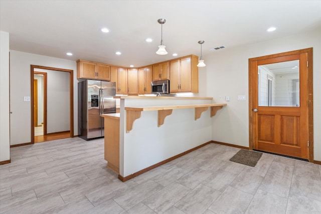 kitchen featuring stainless steel appliances, a breakfast bar area, kitchen peninsula, and pendant lighting