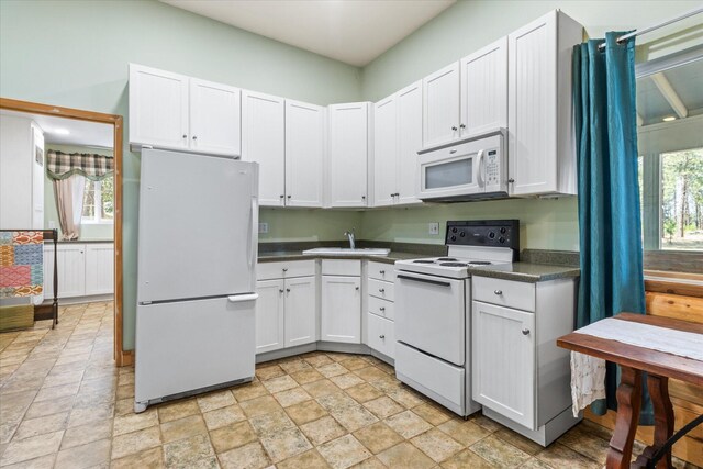 kitchen with white cabinets, sink, white appliances, and light tile patterned floors