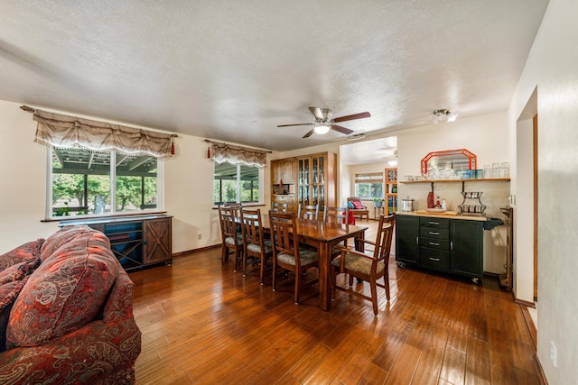 dining area featuring a textured ceiling, dark wood-style flooring, and a wealth of natural light