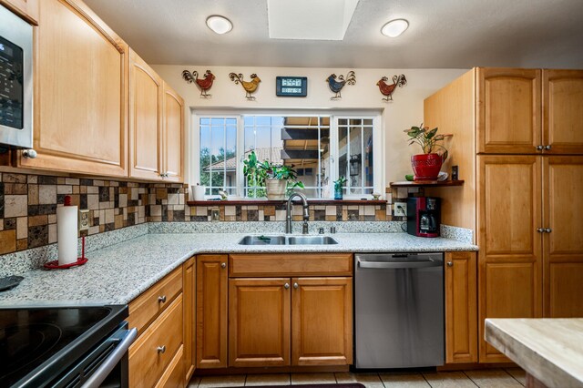 kitchen featuring sink, decorative backsplash, light stone countertops, light tile patterned flooring, and dishwasher