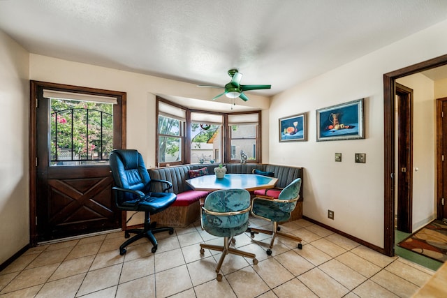 dining area with light tile patterned floors, a ceiling fan, baseboards, and a textured ceiling