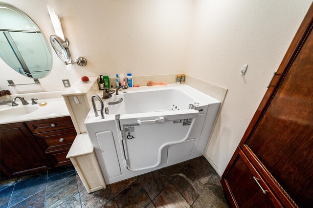 bathroom with a tub, vanity, and tile patterned floors