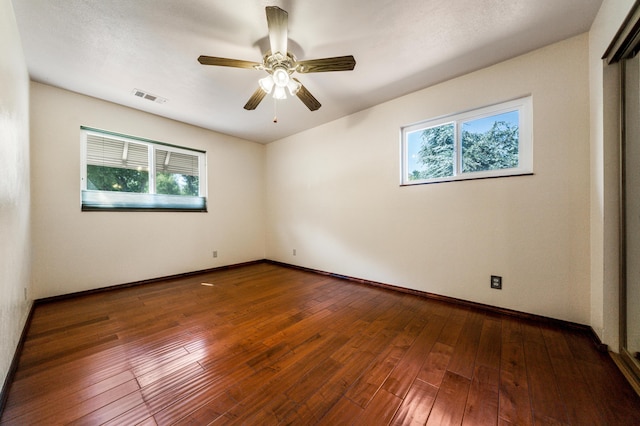 spare room with a wealth of natural light, wood finished floors, and visible vents