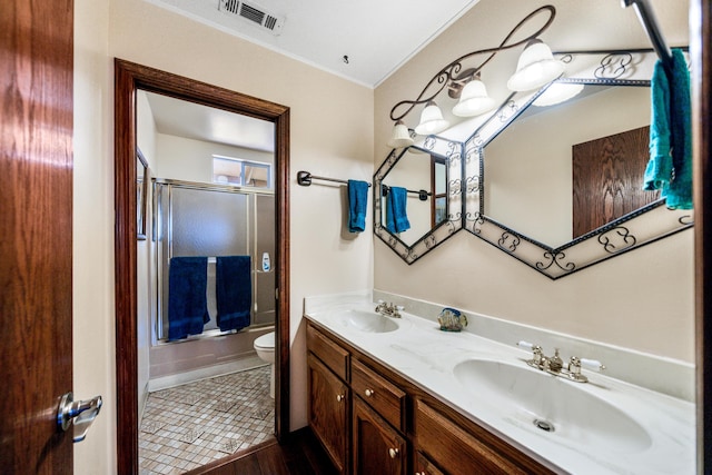 full bathroom with tile patterned floors, double vanity, ornamental molding, enclosed tub / shower combo, and toilet