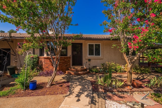 single story home with a tile roof, brick siding, and stucco siding