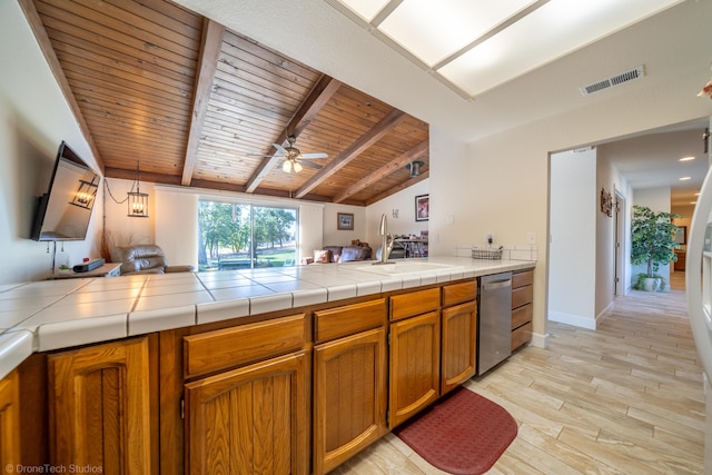 kitchen featuring visible vents, dishwasher, tile countertops, light wood-style floors, and a sink