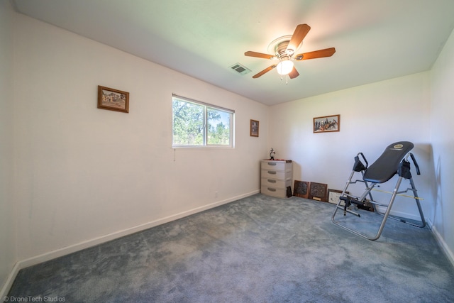 exercise area featuring dark colored carpet, visible vents, ceiling fan, and baseboards