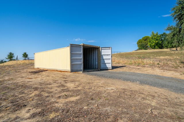 view of outdoor structure featuring fence and a rural view