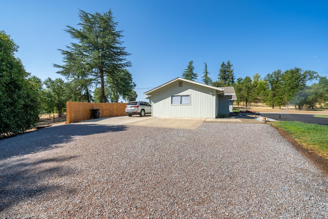 view of property exterior with gravel driveway and fence