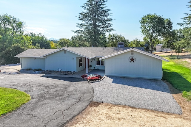 ranch-style home with a shingled roof and aphalt driveway