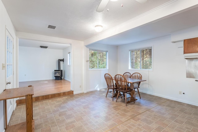 dining room featuring ceiling fan and a wood stove