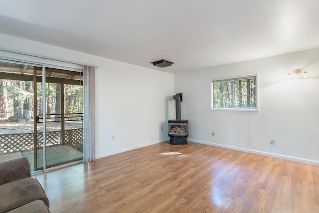 unfurnished living room with plenty of natural light, light hardwood / wood-style flooring, and a wood stove