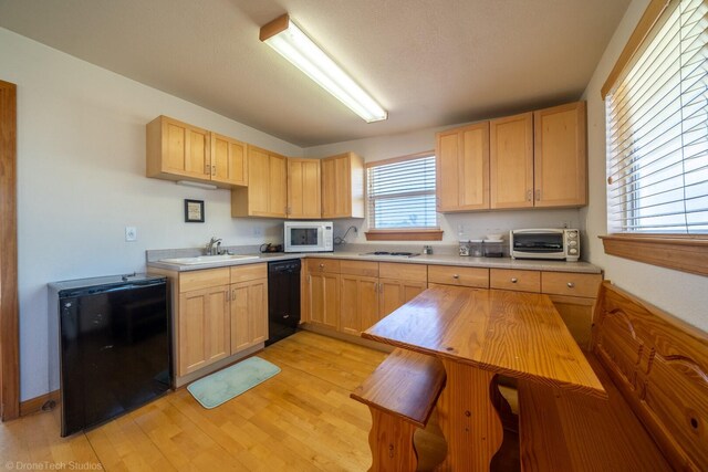 kitchen with light hardwood / wood-style flooring, black dishwasher, light brown cabinetry, refrigerator, and sink