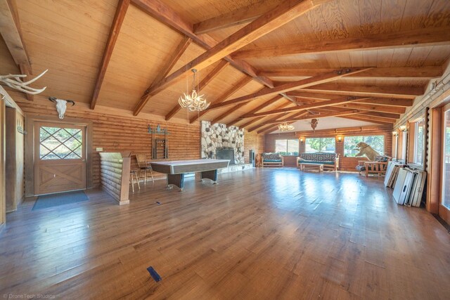 unfurnished living room featuring a stone fireplace, a notable chandelier, wood-type flooring, wooden ceiling, and lofted ceiling with beams