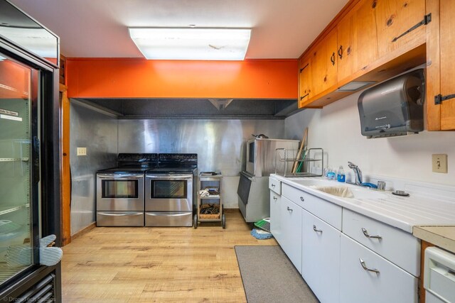 kitchen with appliances with stainless steel finishes, sink, and light hardwood / wood-style floors