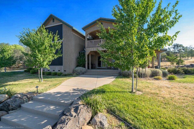 view of front of property featuring a balcony and a front yard