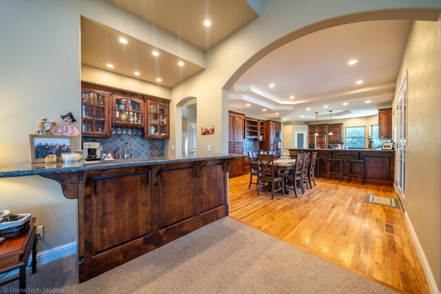 kitchen featuring pendant lighting, decorative backsplash, a breakfast bar, light hardwood / wood-style flooring, and kitchen peninsula