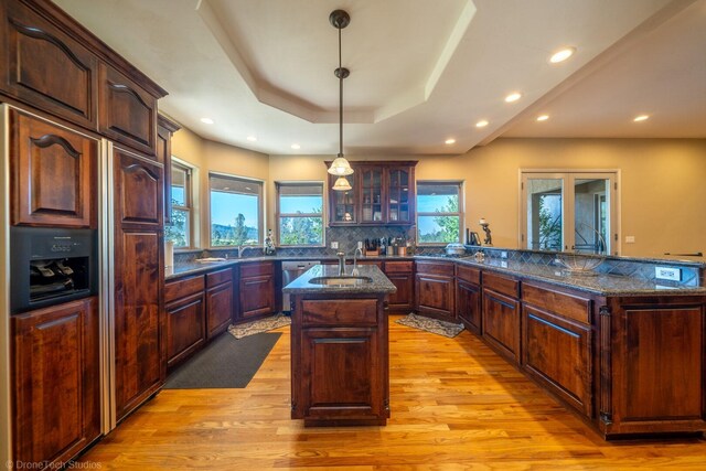 kitchen featuring paneled fridge, a wealth of natural light, pendant lighting, and light hardwood / wood-style floors