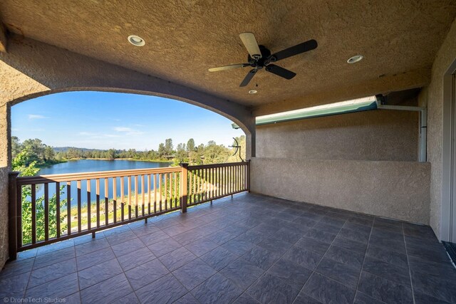 balcony featuring a water view and ceiling fan