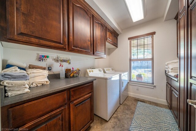 laundry room featuring washer and dryer, light tile patterned floors, and cabinets