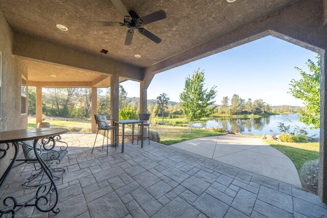 view of patio with a water view and ceiling fan